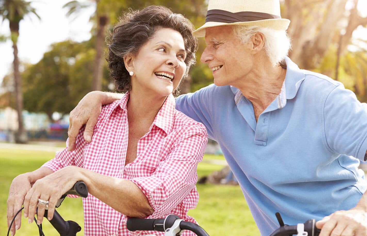 A senior man and woman riding bikes together outdoors