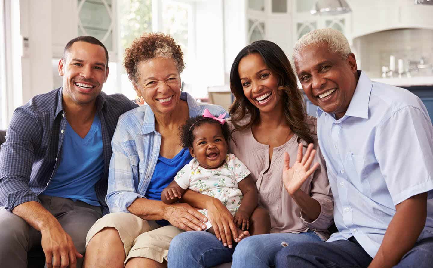 Multi generational family, grandparents, parents and child, smiling and waving.
