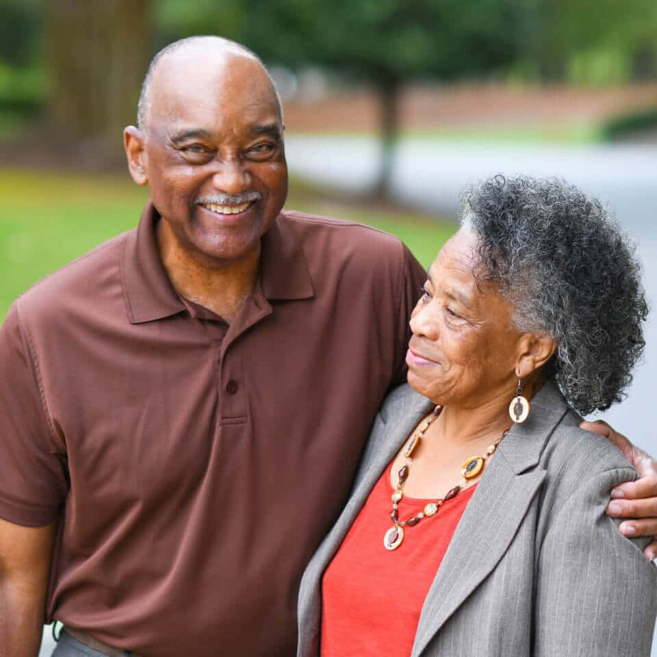 Senior couple with arms around each other smiling