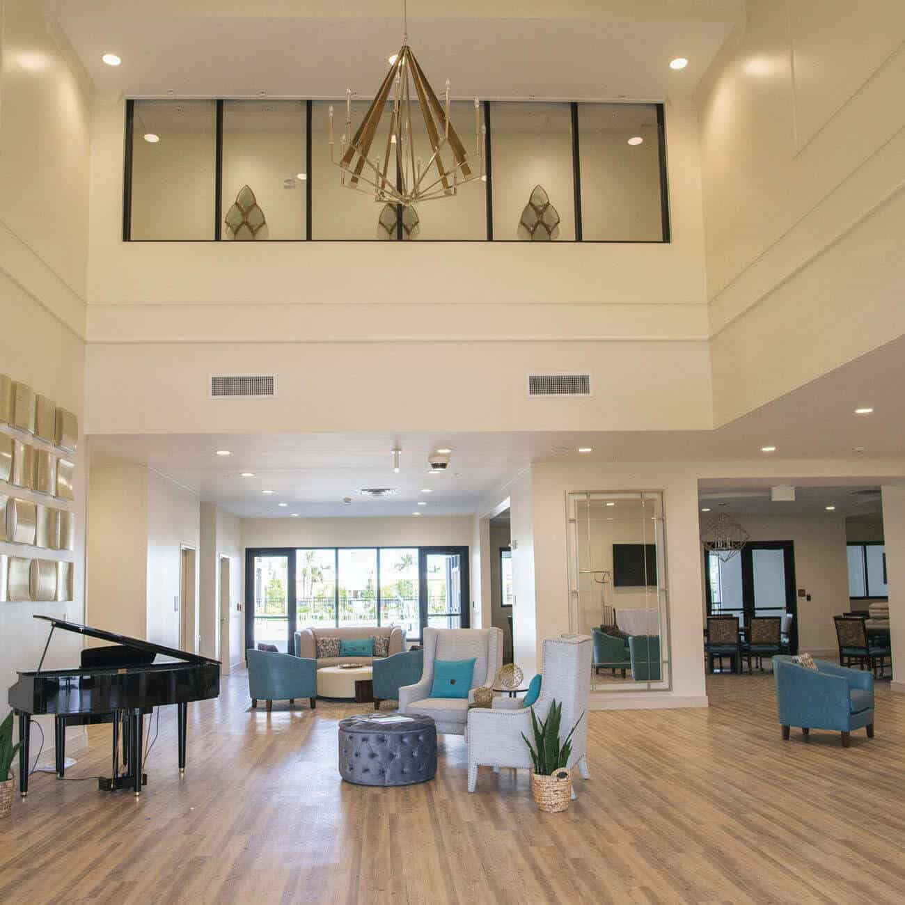 Lobby at Highpoint at Cape Coral includes piano, multiple seating areas and large windows.