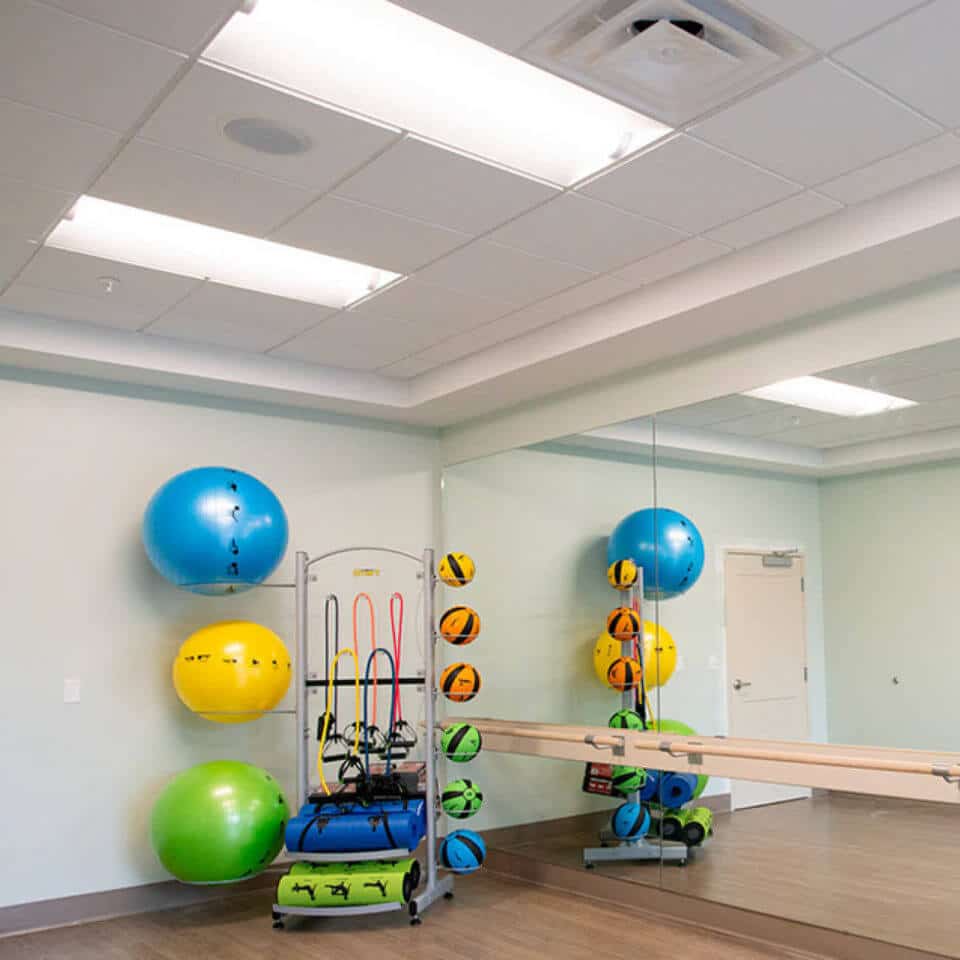 Fitness room at Highpoint at Cape Coral including large mirror, ballet bar, various weighted balls and other exercise accessories.