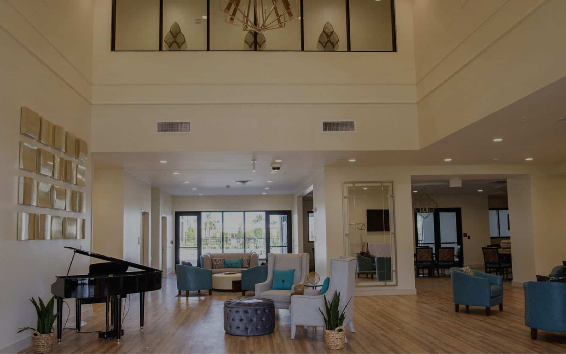 Lobby at Highpoint at Cape Coral includes piano, multiple seating areas and large windows.