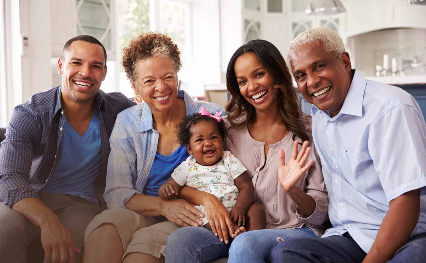 Multi generational family, grandparents, parents and child, smiling and waving.
