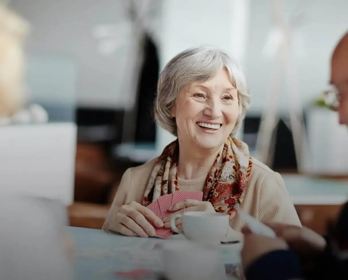 elderly woman playing card and drinking coffee with friends